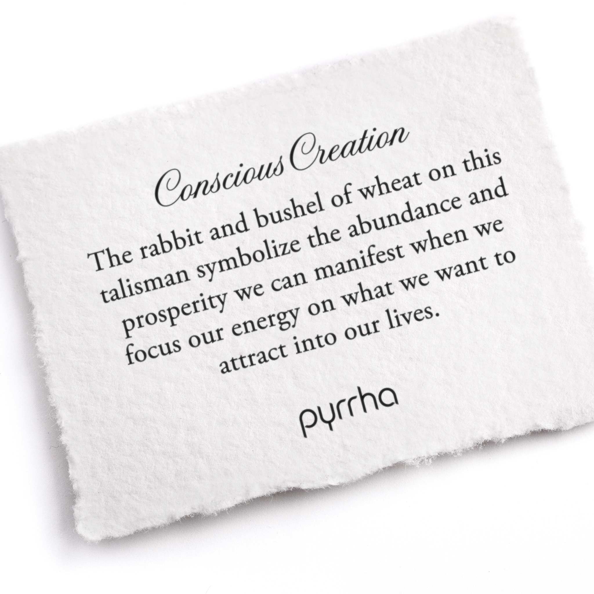 A hand-torn, letterpress printed card describing the meaning for Pyrrha's Conscious Creation Talisman