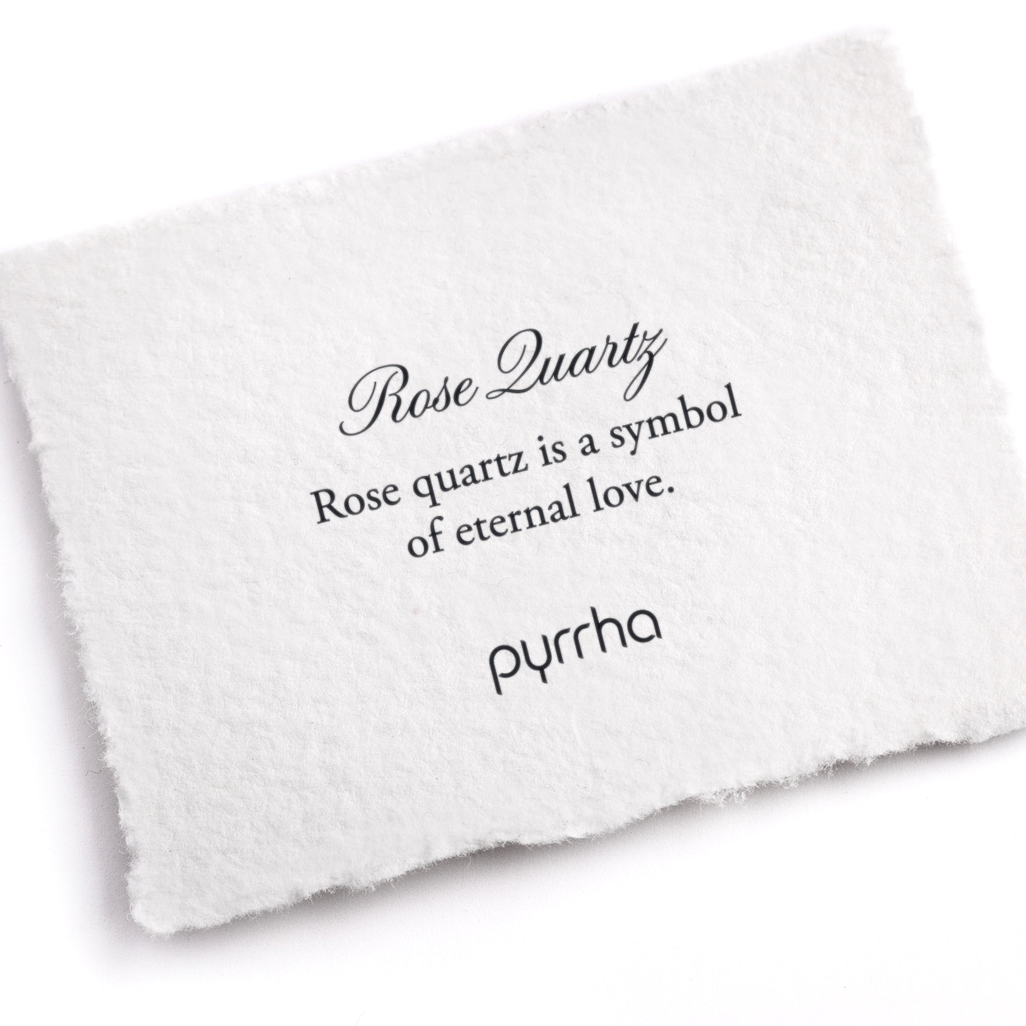 A hand-torn, letterpress printed card describing the meaning for Pyrrha's Rose Quartz stone