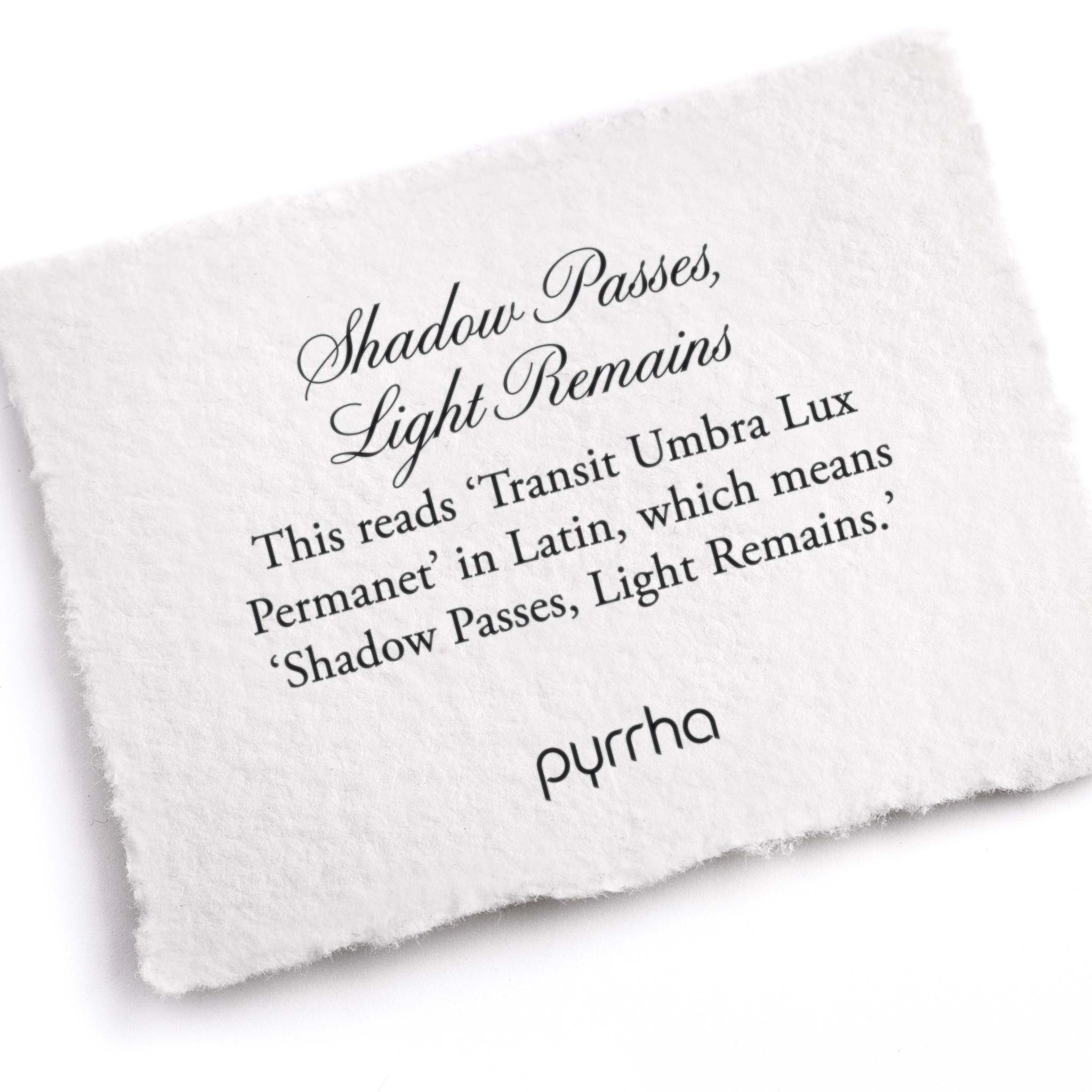 A hand-torn, letterpress printed card describing the meaning for Pyrrha's Shadow Passes, Light Remains Latin Motto Band Ring